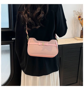 Detalle del bolso rosa con forma de gato, lazo y herrajes dorados sobre un vestido