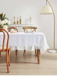 Detail van wit jacquard tafelkleed met elegante kant op een houten tafelblad