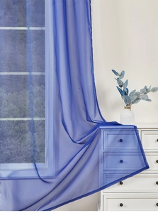 Detail of blue sheer outdoor curtain draped over a white dresser with scenic view