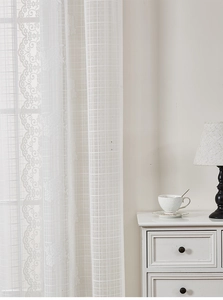 Detail of white French lace curtain featuring floral embroidery and scalloped edges