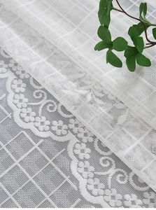 Macro detail of white French lace curtain with delicate floral embroidery and sheer texture