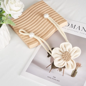 Detail of woven floral curtain tieback with jute rope and large decorative pearls