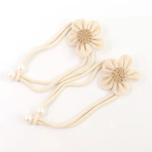 Detail of hand-woven floral curtain tieback with beige cotton petals and pearl accents