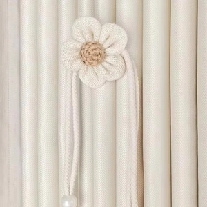 Detail of hand-knitted flower curtain tieback with white petals and pearl pendant