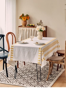 Close-up of Nordic linen tablecloth with yellow geometric embroidery and cross-stitch edges