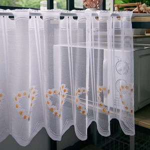 Macro detail of white lace cafe curtain with yellow heart embroidery and wavy edges