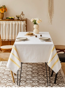 Close-up of geometric yellow embroidery on a white waterproof rectangular tablecloth