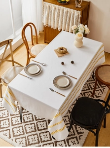 Detail of white cotton linen tablecloth featuring yellow embroidery and Nordic aesthetic