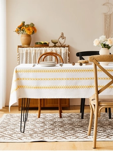 Close-up of yellow floral embroidery detail on white rectangle cotton linen tablecloth