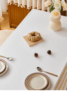 Detailed view of white cotton tablecloth edge with yellow embroidery and soft fringe