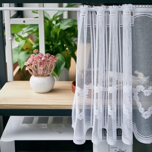 Close-up of white lace cafe curtain featuring heart patterns and scalloped lace edges