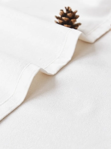 Detail shot of white linen tablecloth with clean stitched edges and natural fabric texture
