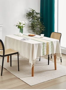 Detail of leaf embroidery and white fringe tassel on linen tablecloth for dining tables