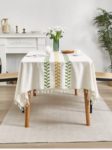 Close-up of Nordic style tablecloth featuring green leaf embroidery and delicate tassels