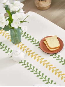 Detail of embroidered yellow and green leaves on high-quality white linen tablecloth texture