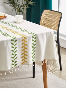 Close-up of rectangular tablecloth with embroidered leaf patterns and tassel edges
