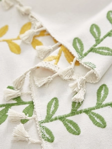 Close-up of botanical embroidery and tassel edges on linen cotton tablecloth