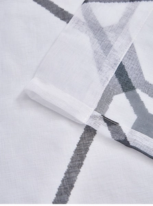 Detail view of plaid sheer curtain fabric showing textured cotton weave and hem stitching