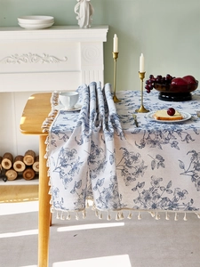 Detailaufnahme der Vintage-Leinentischdecke mit blauen Blumenmustern und weißen Fransen