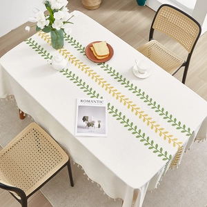 White linen tablecloth with yellow-green leaf embroidery and beige tassel edges