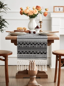 Detail of woven table runner with black and white geometric patterns and cream tassels