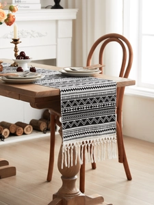 Detailed view of black and white bohemian table runner with woven geometric patterns and tassels