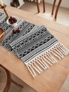 Detail of woven table runner with black and white geometric patterns and boho tassels