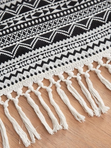 Detailed view of woven table runner with black and white geometric patterns and tassels
