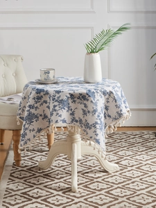 Detail of vintage floral cotton linen tablecloth featuring blue patterns and fringe tassels