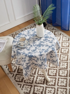 Detail view of floral cotton linen tablecloth with elegant cream fringe edges on round table
