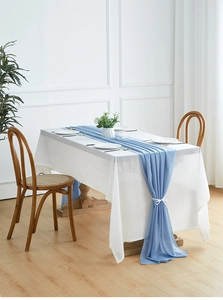 Close-up of sky blue chiffon table runner with draped ribbon over a white tablecloth