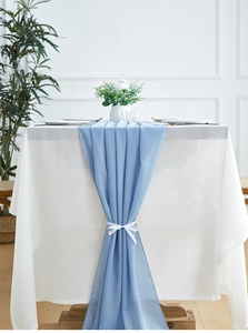 Close-up of light blue chiffon table runner tied with a white ribbon bow on table