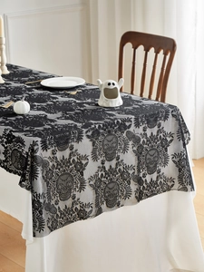 Detailed view of black lace Halloween tablecloth featuring intricate skull and flower patterns