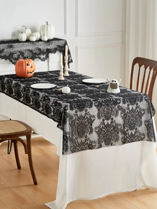 Detail of black lace Halloween tablecloth with skull patterns over a white base