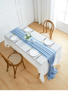 Detail view of light blue chiffon table runner with natural draping folds on white cloth