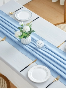 Close-up of light blue chiffon table runner with elegant pleats and gold tableware