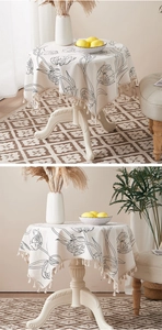 Close-up of beige cotton linen tablecloth with black tulip patterns and tassel edges