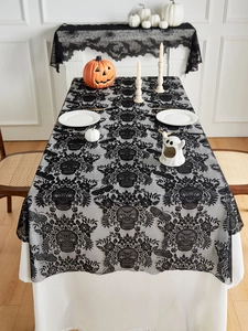 Detail of black lace Halloween tablecloth featuring intricate skull patterns and floral mesh
