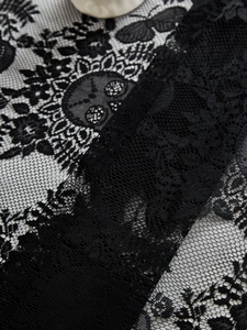 Close-up of black lace tablecloth featuring intricate skull and floral embroidery details