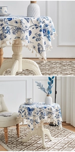 Detail of floral linen tablecloth featuring blue birds and elegant beige tassels