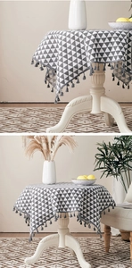 Detailed close-up of a round tablecloth with grey geometric patterns and elegant tassels