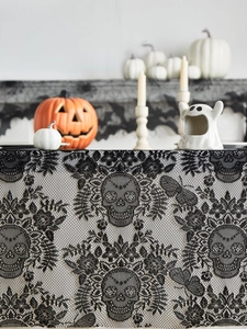 Detail of black lace Halloween table runner featuring skulls, moths and vintage patterns