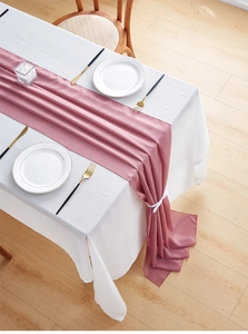 Detail of elegant dusty pink chiffon table runner cascading gracefully onto light wood floor