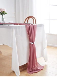 Close-up of elegant rose pink chiffon table runner tied with a delicate white silk ribbon
