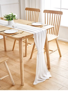 Detail of white chiffon table runner with elegant ribbon tie on a wooden table