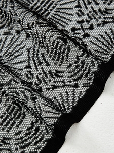 Detailed close-up of black lace curtain fabric with intricate gothic hollow patterns