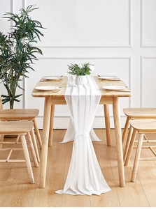 Detail of white chiffon table runner draped on wood with decorative ribbon tie