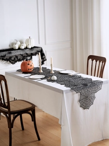 Détail d'un chemin de table en dentelle noire avec motifs de toile d'araignée et chauve-souris