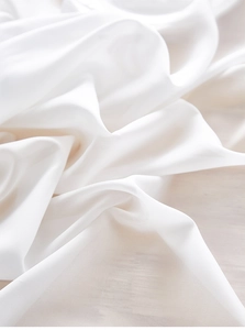 Detailed close-up of white chiffon fabric texture with soft drape on wooden table