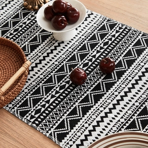 Geometric black and white woven table runner with fringes on a wooden table setup
